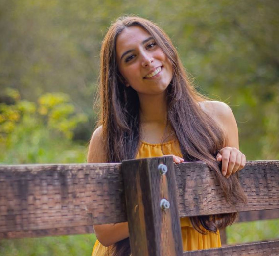 A main with a mustache wearing a brown t-shirt and necklace